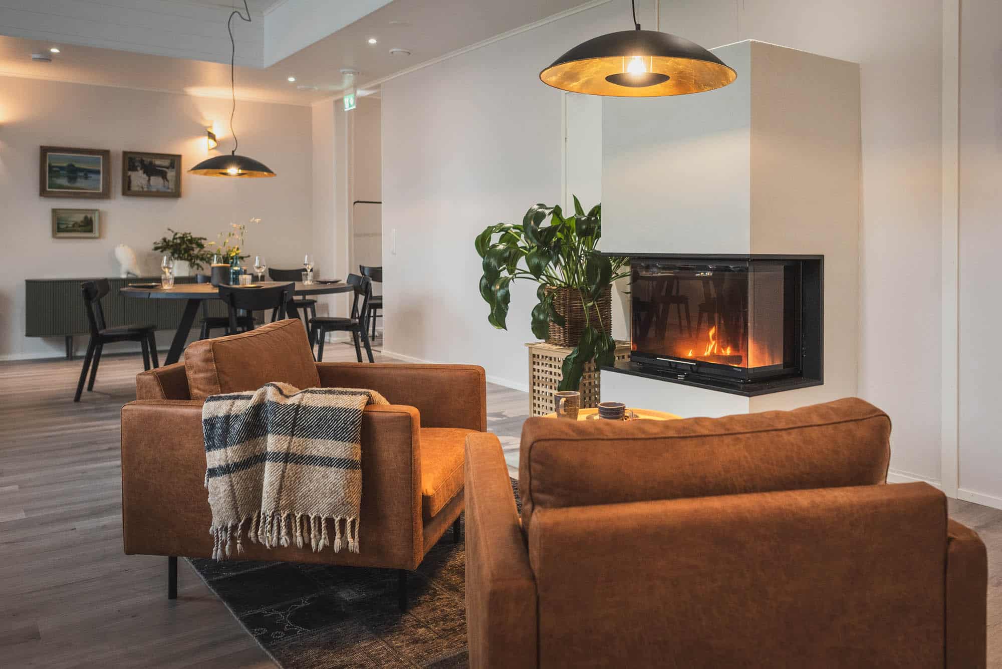 Cozy lounge and dining area with fireplace at Lehtiniemi Guesthouse in Posio, Finnish Lapland.